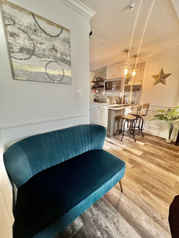 A living room with a blue sofa, a kitchen in the background, and a star decoration on the wall.