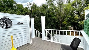 A wooden deck with white railings, a yellow plunger, and two black wicker chairs. - Historic Love, Modern Appeal C (Haines City)