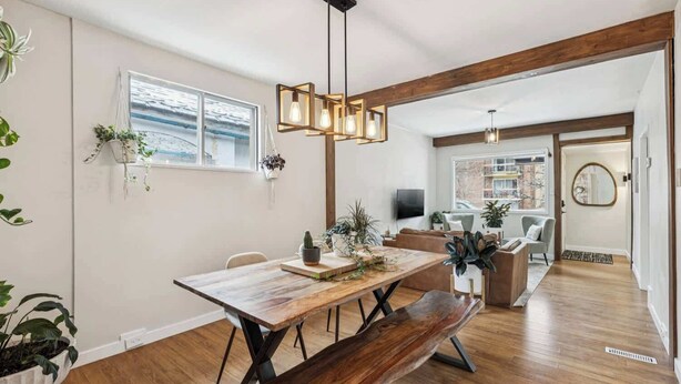 A modern dining area with a wooden table, bench, and hanging light fixture. - Trendy Kensington | Espresso Maker| Garage| AC (Calgary)