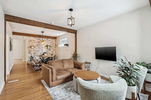 Uma sala de estar moderna com um sofá de couro, uma mesa de centro redonda e uma TV fixada na parede.
