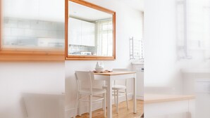 A bright room with a wooden-framed mirror, a white table with chairs, and a view of a kitchen through the window. - Peaceful Hidden Gem, Heart of South East London (London)