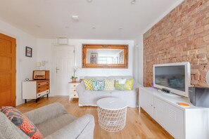 A modern living room with a sofa, a TV, and a brick wall. - Peaceful Hidden Gem, Heart of South East London (London)