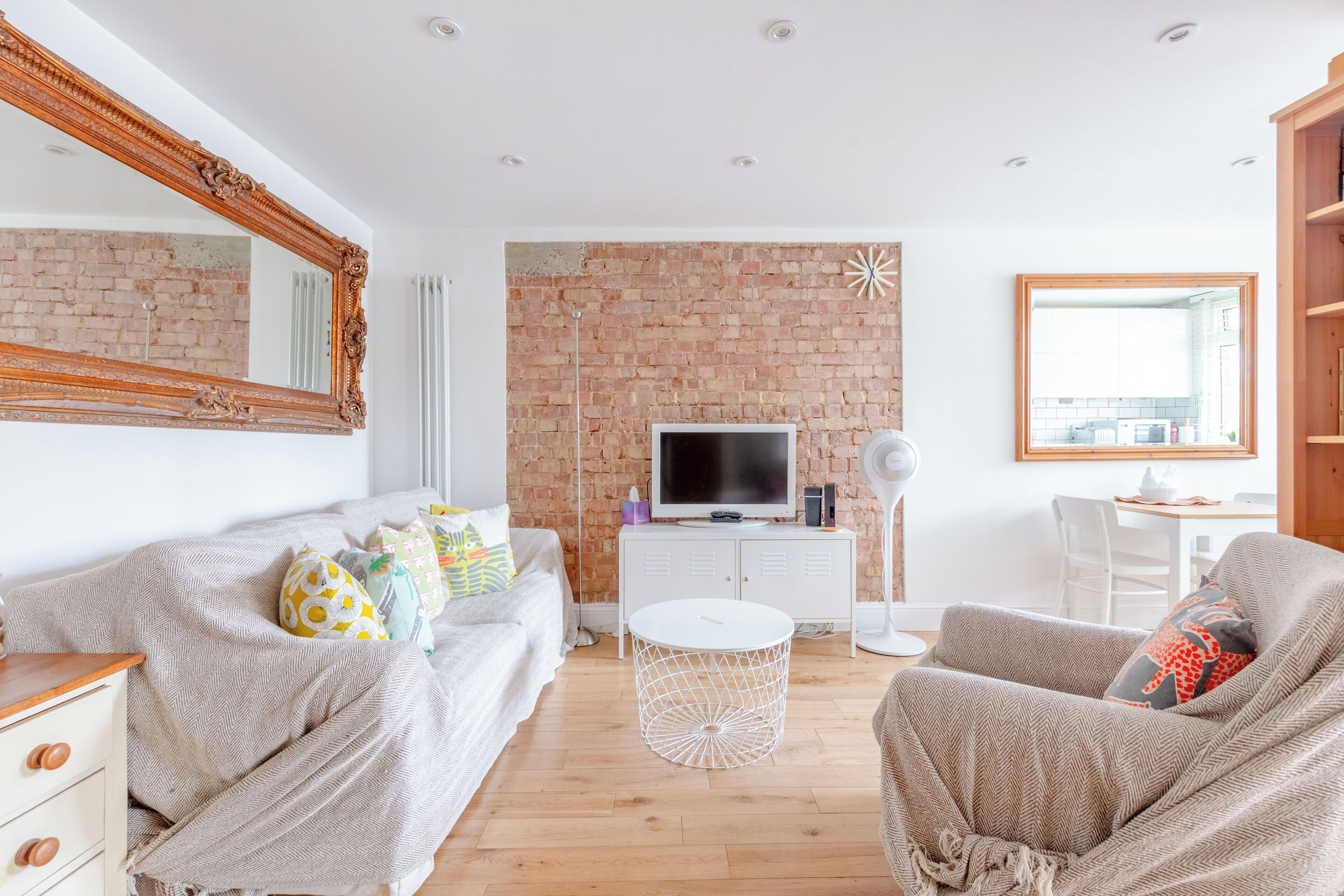 A modern living room with a brick wall, a television, a white round coffee table, and a comfortable seating area.