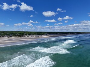 A coastal beach with waves, a sandy shore, and a forested area in the background. - Seacastles Resort (Ogunquit)