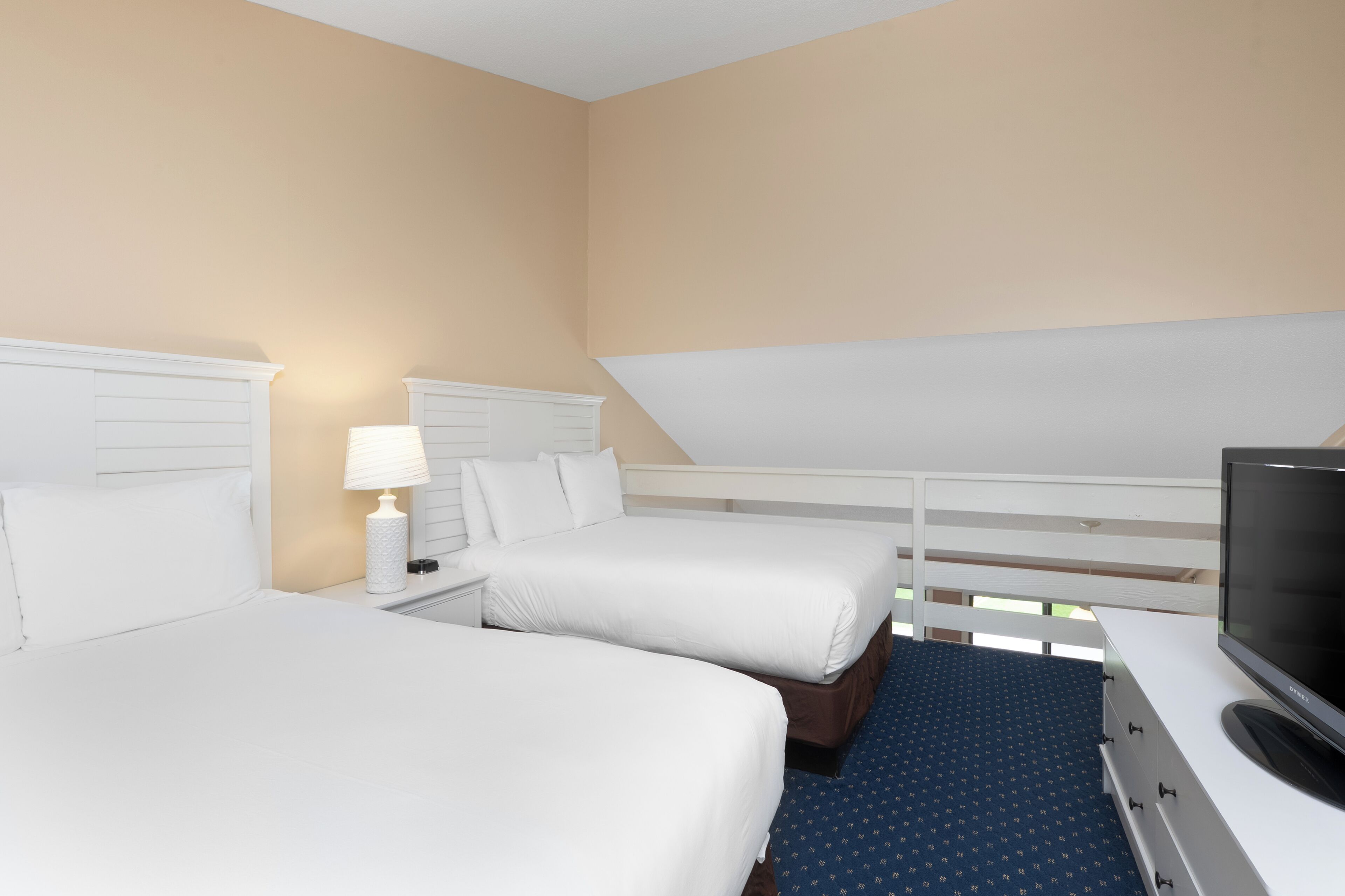 A hotel room with two beds, a TV, and a window with a view.