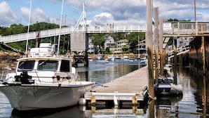 Un puerto deportivo con barcos amarrados, un muelle de madera y un puente al fondo.