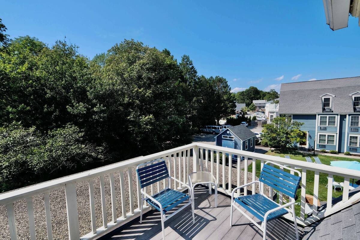 A wooden deck with white railings and blue chairs.