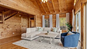A wooden interior with a sectional sofa, a coffee table, and a blue armchair. - Pisgah Paradise • Private • Game Room • Large Deck (Pisgah Forest)