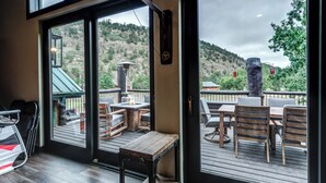 Um terraço ao ar livre com móveis de madeira e vista para uma paisagem montanhosa.