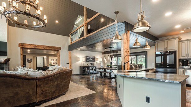 Uma cozinha espaçosa com uma ilha central, uma área de jantar com uma mesa grande e um espaço de estar acolhedor com um sofá.