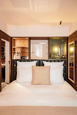 A hotel room with a large bed, a wooden wardrobe, a mirror, and a small seating area. - Hôtel Florida Paris (Paris)