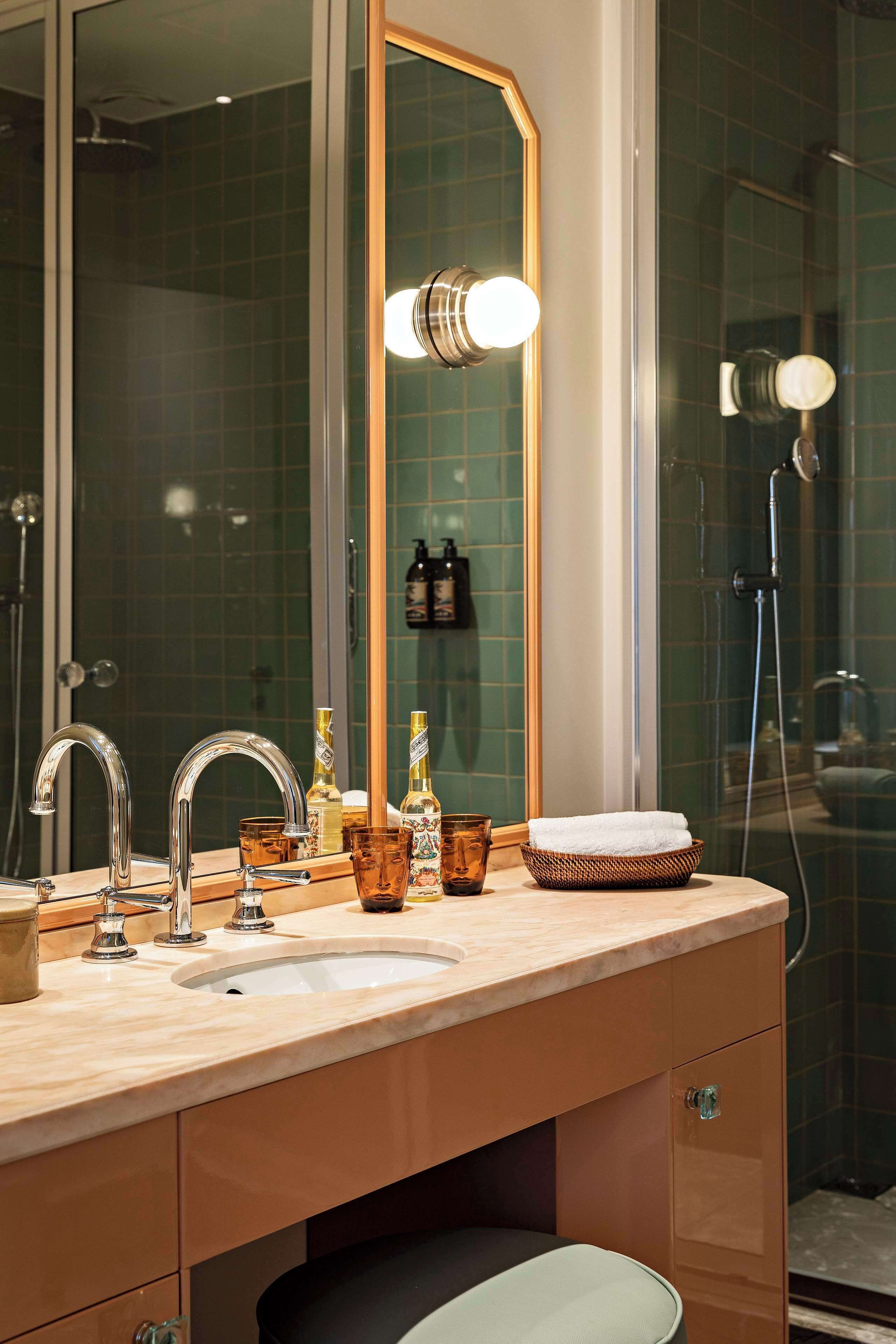 A bathroom with a large mirror, two sinks, a shower, and a towel rack.