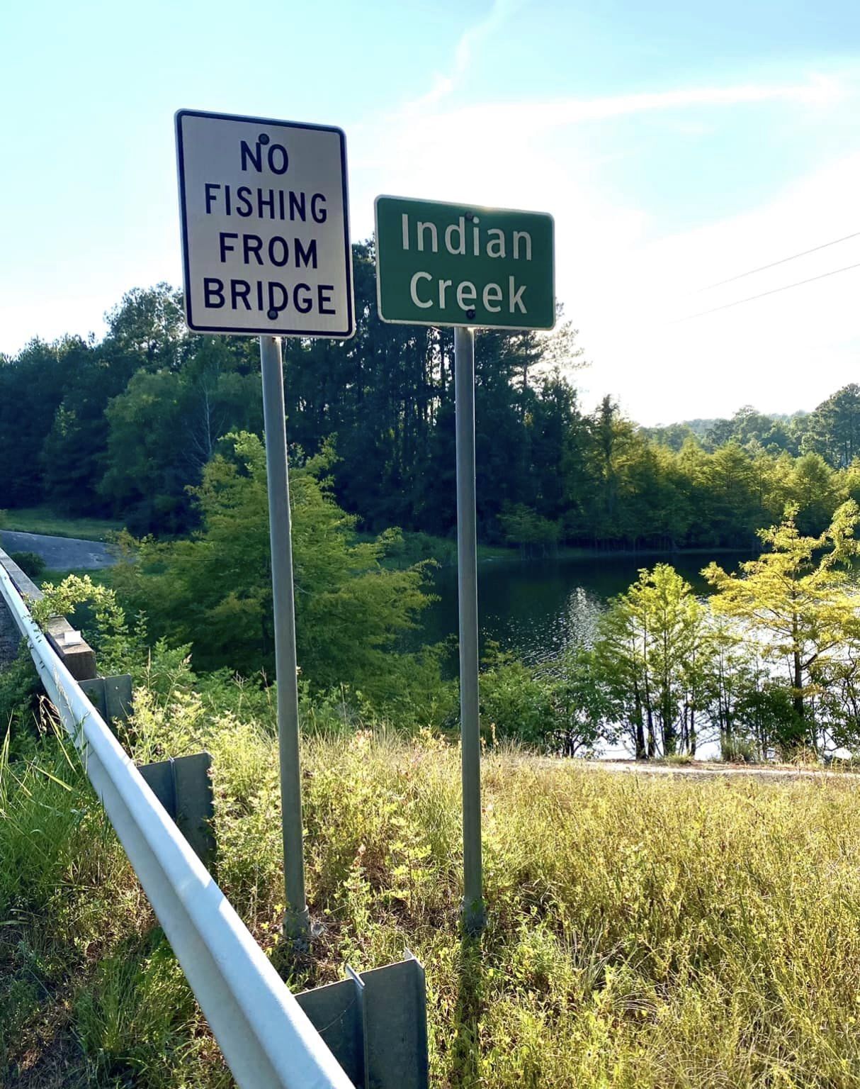 Señal de tráfico que indica 'No se permite pescar desde el puente' y 'Arroyo Indian Creek'.