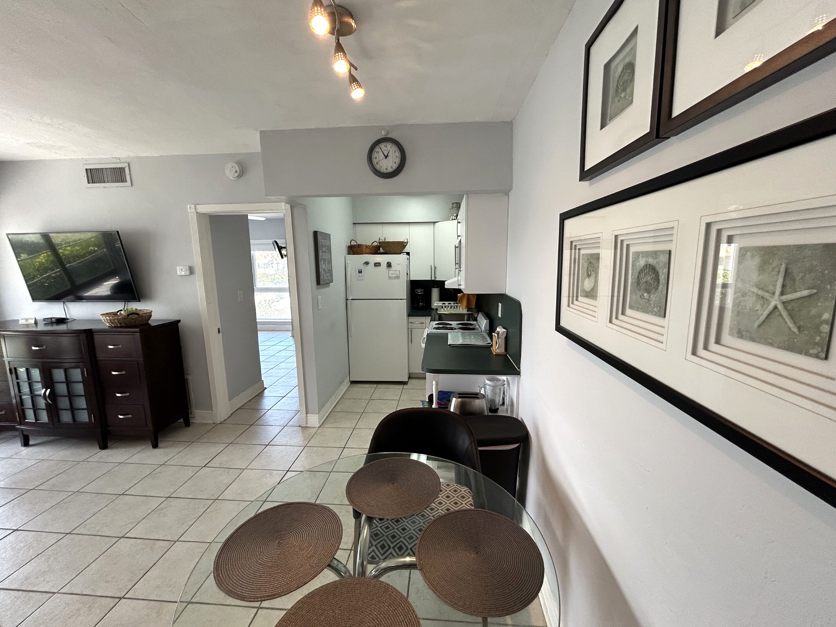 A modern kitchen with a refrigerator, stove, and dining area with a glass table and chairs.