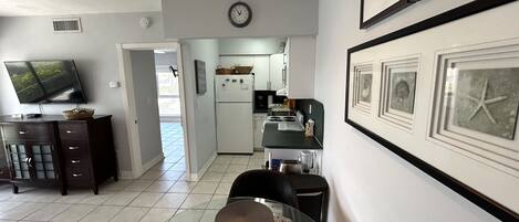 A modern kitchen with a refrigerator, stove, and dining area with a glass table and chairs.