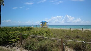 Une tour de surveillance sur une plage, avec un ciel dégagé et l’océan en arrière-plan.