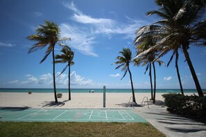 A beach with a shuffleboard court, palm trees, and a clear blue sky. - Shore View Hotel (Hollywood)