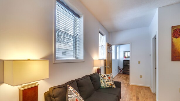 Una sala de estar con un sofá, dos cojines estampados, una lámpara y una mesa de centro de madera.