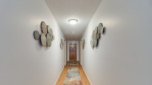 Un pasillo con piso de madera, un tapete colorido y decoración en las paredes.