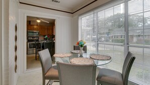 Un comedor con una mesa de vidrio, sillas y vistas a la cocina a través de un acceso.