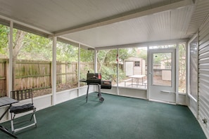A covered patio with a grill, a table, and a bench.