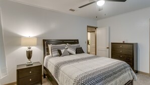 Un dormitorio con cama, mesita de noche, cómoda y ventilador de techo.