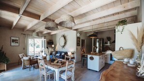 Une cuisine spacieuse avec des poutres en bois, un coin repas avec une table et des chaises en bois, et un salon confortable avec un canapé et une cheminée.