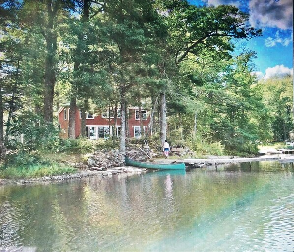 A house by a lake with a dock and a canoe. - STUNNING WATERFRONT HOME ON PITCHER POND - LINCOLNVILLE. 3 bedrooms, 3 baths! (Lincolnville)