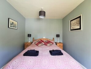 Une chambre à coucher avec un lit, deux tables de chevet et un luminaire au plafond.