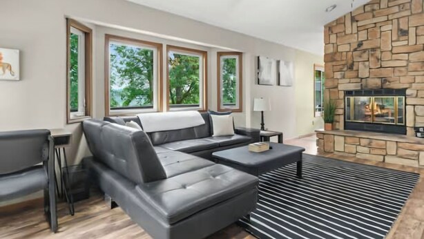 Un salon moderne avec un canapé d’angle, une cheminée et de grandes fenêtres.