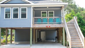 A two-story house with a covered front porch, a wooden staircase, and a garage. - Hale Aloha: An Aloha-Inspired Escape in the OBX (Kill Devil Hills)
