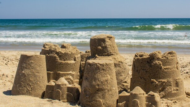 A sandy beach with sand structures resembling castles. - Hale Aloha: An Aloha-Inspired Escape in the OBX (Kill Devil Hills)
