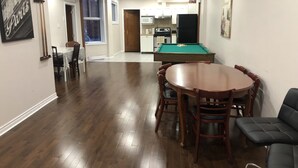 A spacious living room with a pool table, wooden dining table, and chairs. - Spacious 3 beds Loft with Parking($14/day) (Montréal)
