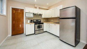 A modern kitchen with white cabinets, a stainless steel refrigerator, a microwave, and a stove. - Spacious 3 beds Loft with Parking($14/day) (Montréal)