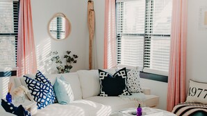 A modern living room with a white sofa, blue and black patterned pillows, a round coffee table, and a large mirror on the wall. - NEW boutique, luxury rental in Downtown Petoskey! Dogs welcome! (Petoskey)
