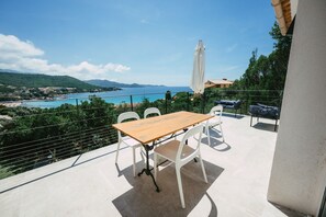 Enjoy a tranquil outdoor space with a table and chairs, overlooking a serene coastal landscape.