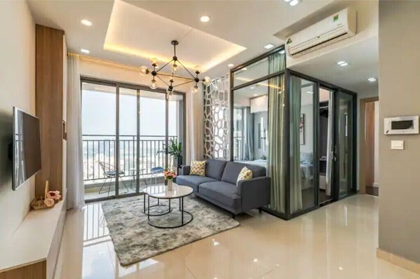 A modern living room with a grey sofa, a coffee table, and a TV on the left wall.