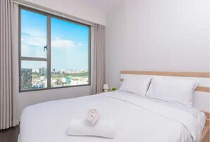 Ein Hotelzimmer mit großem Fenster, einem ordentlich bezogenen Bett und Blick auf die Stadt.