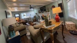 Una sala de estar acogedora con ventilador de techo, chimenea y comedor con mesa y sillas.