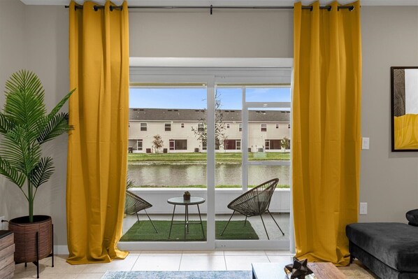 Relax in this stylish living room with a sofa, table, and chairs, and step out to an outdoor area through the sliding glass door.