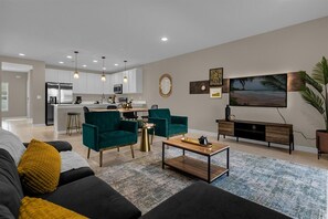 Relax in a spacious living area with a comfortable sofa set and enjoy meal preparation in a clean kitchen with stainless steel appliances.