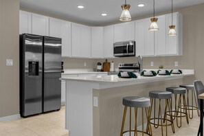 Enjoy cooking and dining in this inviting kitchen with a sleek refrigerator, microwave, and spacious island with bar stools.