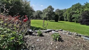 A garden with a variety of plants and a red flamingo statue. - Honeysuckle Cottage (Llanfyrnach)