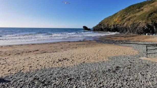 A beach with pebbles and a rocky cliff. - Honeysuckle Cottage (Llanfyrnach)