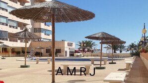 Ein Poolbereich eines Resorts mit mehreren Sonnenschirmen und roten Blumen im Vordergrund.