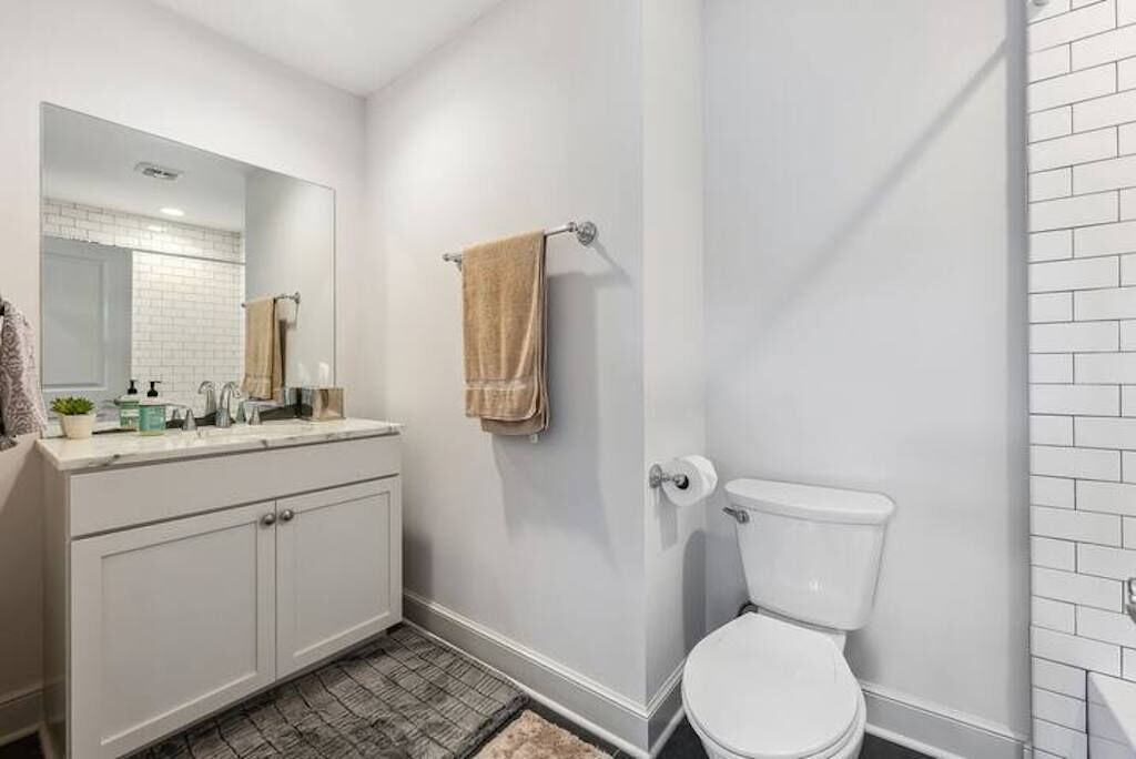 A bathroom with a white toilet, a sink with a mirror, and a towel hanging on the wall.