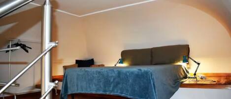 A bedroom with a bed, a desk, and a chair.