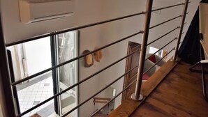 A modern interior with a wooden floor, metal railings, and a window providing a view of the outside. - Chez Angelina Positano (Positano)