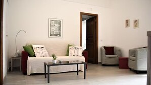 A living room with a sofa, a coffee table, a chair, and a door leading to another room. - Chez Angelina Positano (Positano)
