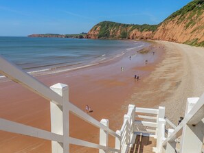 Uma praia com cerca branca e escadas descendo até a orla.